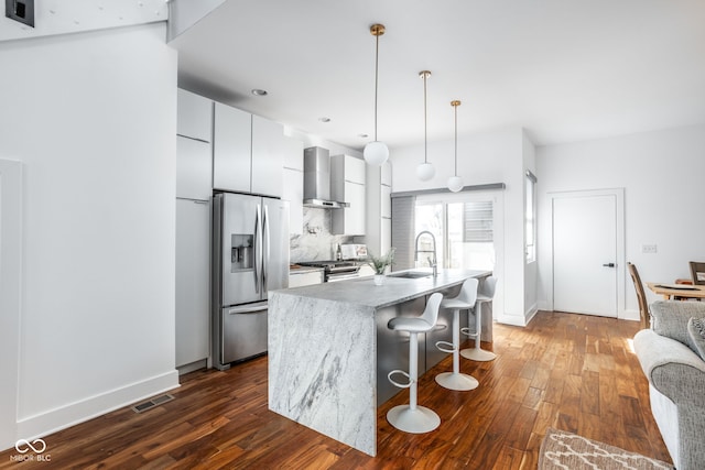 kitchen with visible vents, a sink, appliances with stainless steel finishes, wall chimney range hood, and modern cabinets