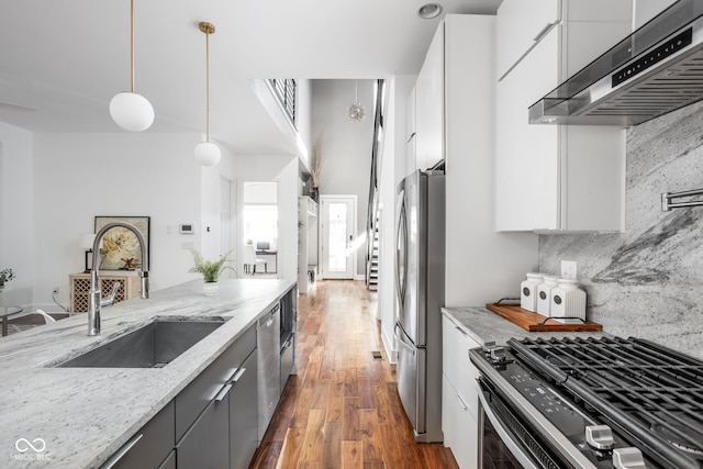 kitchen featuring range hood, a sink, stainless steel appliances, white cabinets, and wood-type flooring