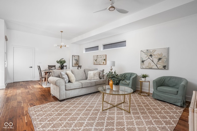 living room featuring ceiling fan with notable chandelier, baseboards, and hardwood / wood-style flooring