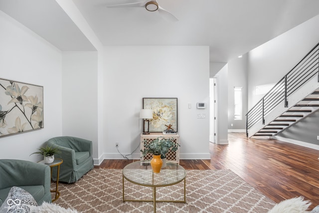 living room with a ceiling fan, stairs, baseboards, and wood finished floors