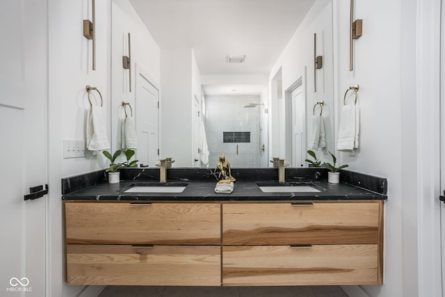 bathroom featuring double vanity, a stall shower, and a sink