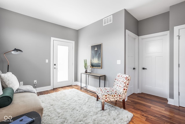 living room featuring visible vents, baseboards, and wood finished floors