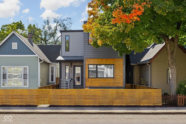 contemporary house featuring a fenced front yard, metal roof, and a standing seam roof