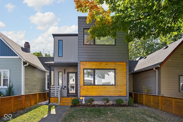 modern home featuring a front yard, fence, and board and batten siding