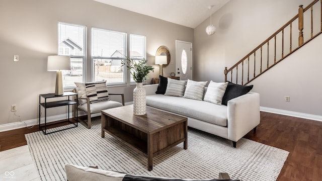 living room featuring wood finished floors, baseboards, and vaulted ceiling