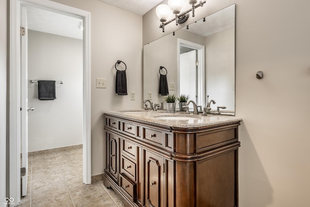 full bathroom featuring double vanity, tile patterned floors, a textured ceiling, and a sink