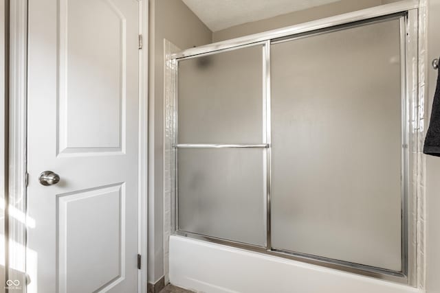 full bathroom with combined bath / shower with glass door and a textured ceiling