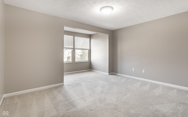 spare room featuring baseboards, carpet floors, and a textured ceiling