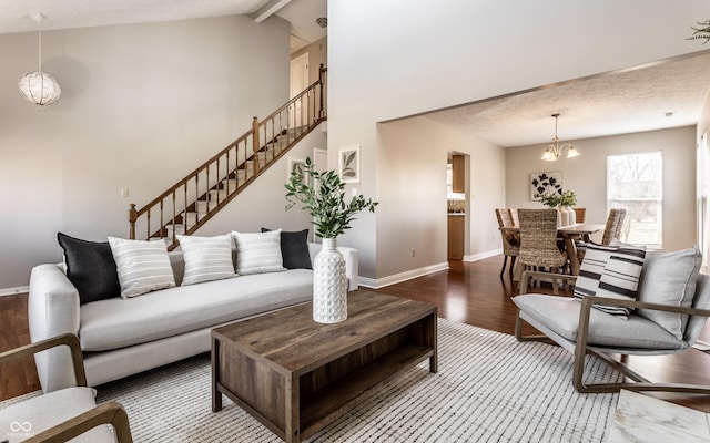 living room with baseboards, a chandelier, stairs, wood finished floors, and high vaulted ceiling