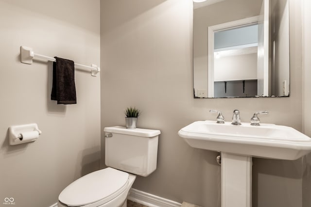 half bathroom with baseboards and toilet