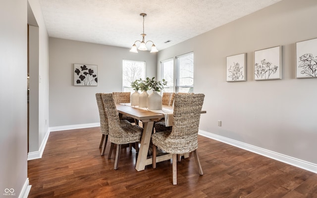 dining space with dark wood finished floors, a textured ceiling, baseboards, and a chandelier