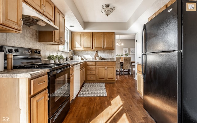 kitchen with dark wood-style floors, black appliances, under cabinet range hood, a raised ceiling, and backsplash