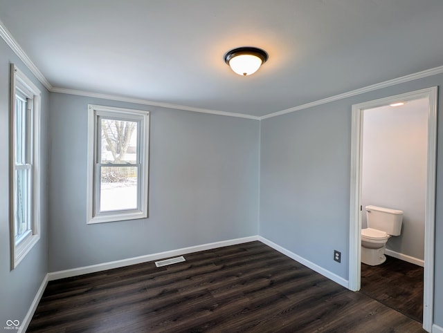 unfurnished bedroom with visible vents, connected bathroom, crown molding, baseboards, and dark wood-style floors