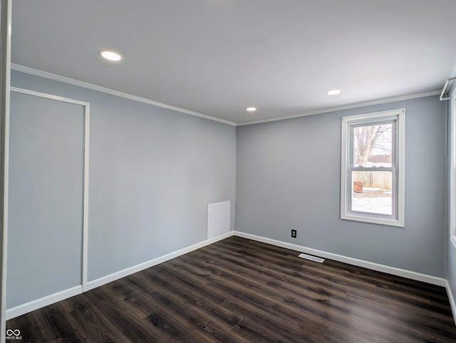 empty room featuring dark wood-style floors, crown molding, and baseboards