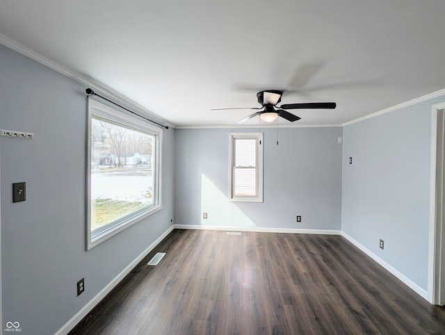 empty room with dark wood-style floors, visible vents, baseboards, and ornamental molding