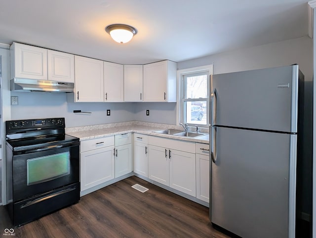 kitchen with black / electric stove, dark wood finished floors, freestanding refrigerator, a sink, and under cabinet range hood