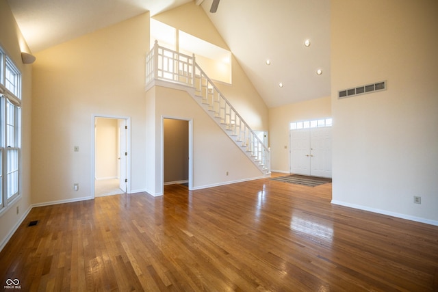 unfurnished living room featuring visible vents, stairs, baseboards, and wood finished floors