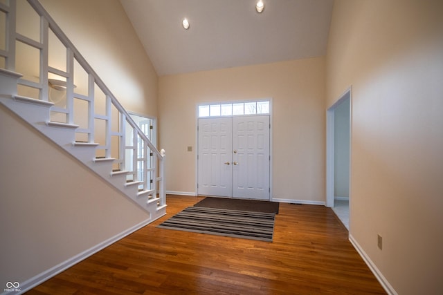 entryway featuring stairs, wood finished floors, baseboards, and high vaulted ceiling