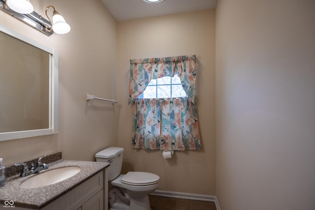 half bathroom with tile patterned flooring, toilet, vanity, and baseboards