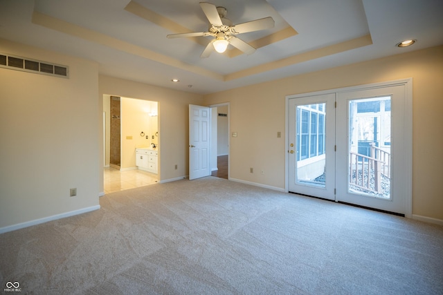 unfurnished bedroom with visible vents, baseboards, access to exterior, a raised ceiling, and light colored carpet