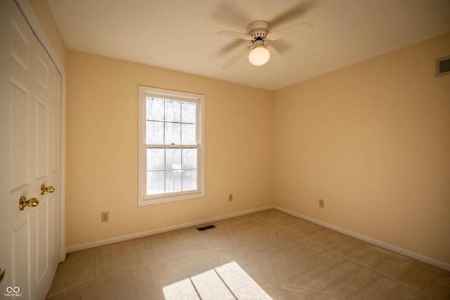 carpeted spare room with baseboards, visible vents, and ceiling fan