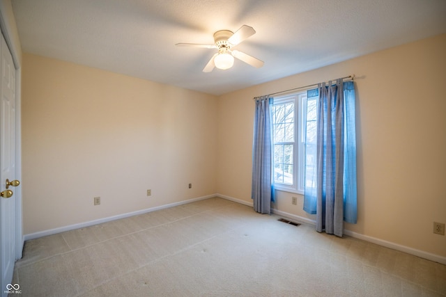 spare room with baseboards, a ceiling fan, visible vents, and light carpet