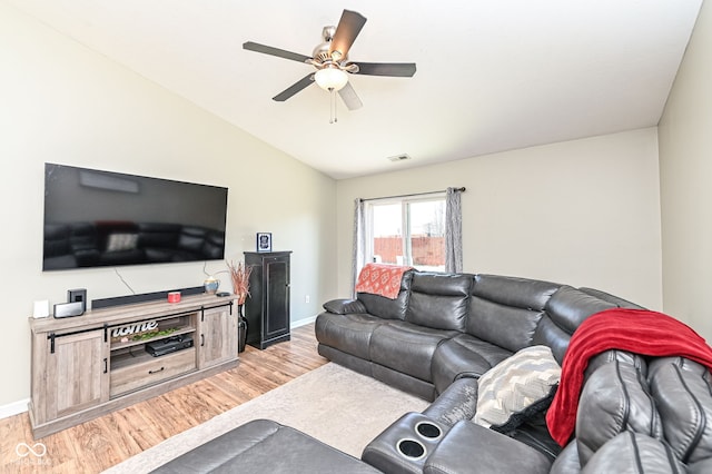 living room featuring visible vents, light wood-style floors, a ceiling fan, and vaulted ceiling