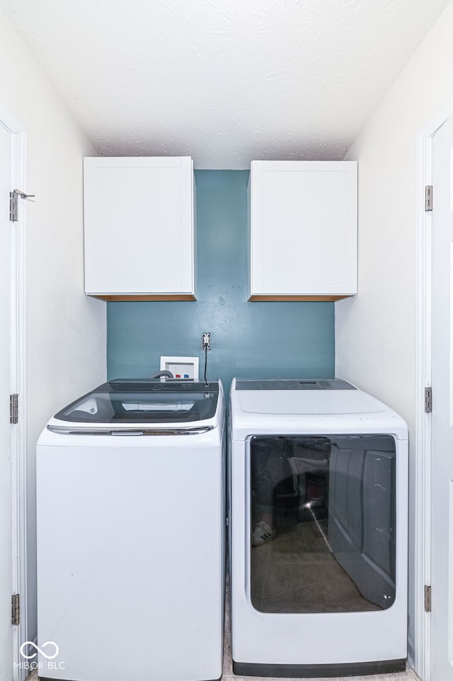 clothes washing area with washing machine and clothes dryer and cabinet space