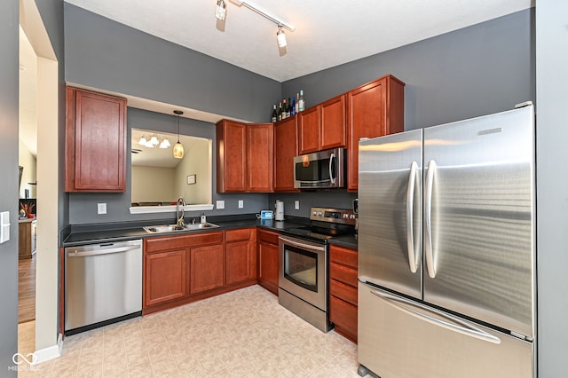 kitchen featuring dark countertops, light floors, appliances with stainless steel finishes, hanging light fixtures, and a sink