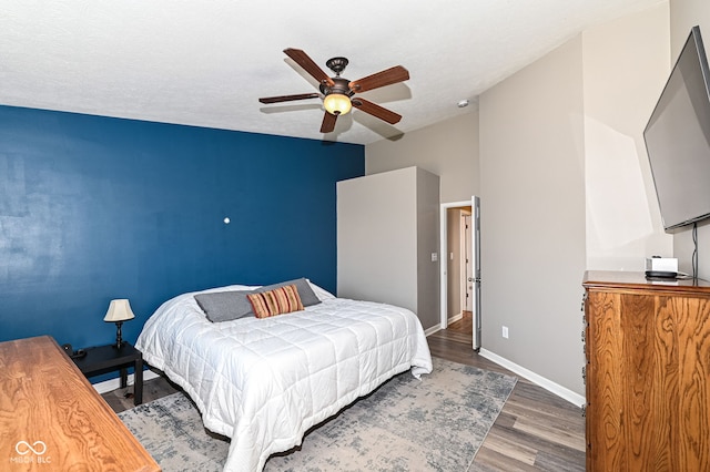 bedroom featuring a ceiling fan, wood finished floors, baseboards, and a textured ceiling