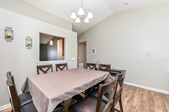 dining room featuring visible vents, a notable chandelier, light wood-style floors, baseboards, and vaulted ceiling