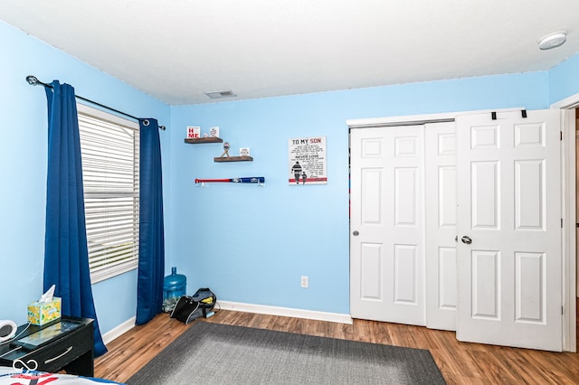 unfurnished bedroom with visible vents, baseboards, a closet, and wood finished floors