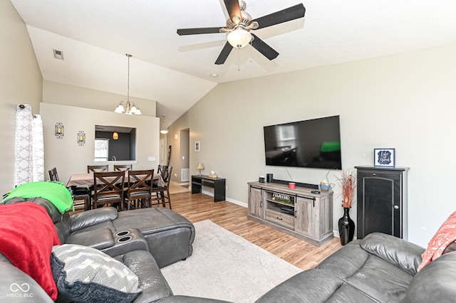 living area with visible vents, baseboards, lofted ceiling, ceiling fan with notable chandelier, and light wood-type flooring