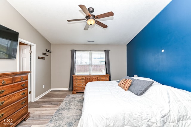 bedroom with visible vents, baseboards, light wood-style floors, and ceiling fan