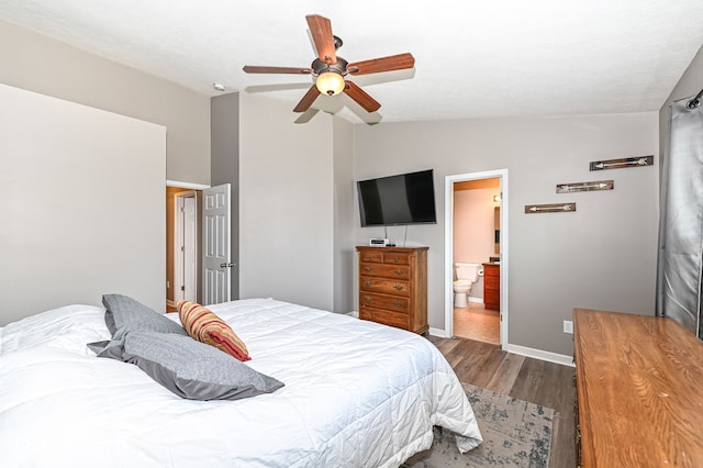 bedroom featuring a ceiling fan, wood finished floors, baseboards, vaulted ceiling, and ensuite bathroom