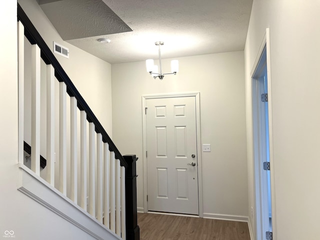entrance foyer with visible vents, a textured ceiling, stairs, and wood finished floors