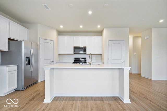 kitchen with visible vents, light wood-type flooring, white cabinets, stainless steel appliances, and a sink