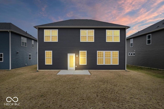 back of property at dusk featuring a yard and a patio