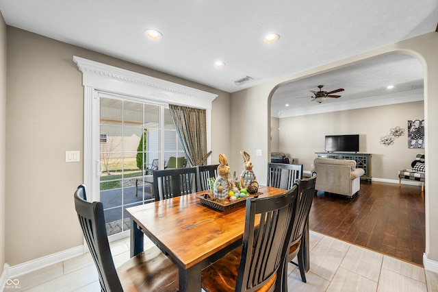 dining space with a ceiling fan, visible vents, light wood finished floors, baseboards, and arched walkways