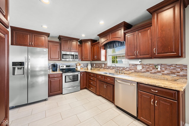 kitchen featuring a sink, stainless steel appliances, light stone counters, and recessed lighting