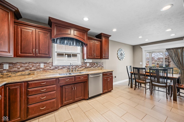 kitchen with light stone counters, baseboards, a sink, dishwasher, and tasteful backsplash