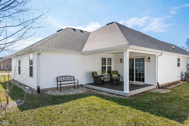 rear view of property featuring a yard, roof with shingles, and a patio area