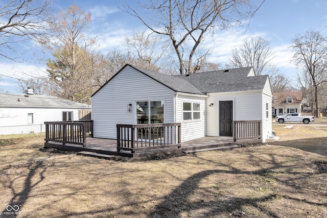 rear view of house featuring fence, roof with shingles, and a wooden deck