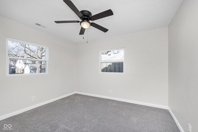 empty room featuring visible vents, baseboards, a ceiling fan, and dark carpet