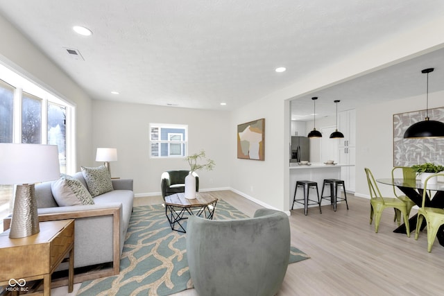 living room featuring recessed lighting, baseboards, and light wood finished floors