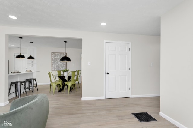 living room with visible vents, baseboards, and light wood-style floors