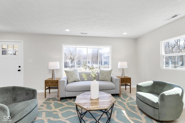 living area with recessed lighting, wood finished floors, visible vents, and baseboards