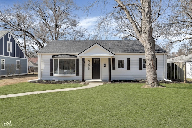 view of front of property featuring roof with shingles, a front yard, and fence