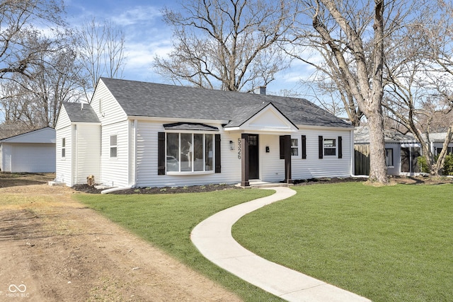 view of front facade featuring a chimney, roof with shingles, and a front yard