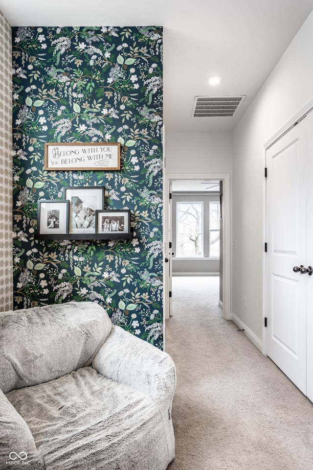 living area featuring visible vents, wallpapered walls, baseboards, and carpet